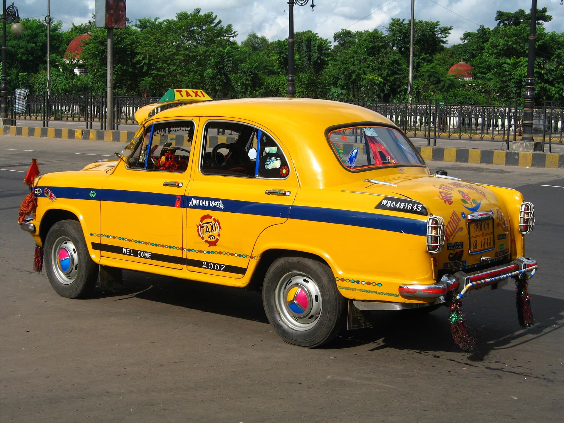 A yellow Ambassador taxi with a blue stripe and hand-painted decorations, Kolkata