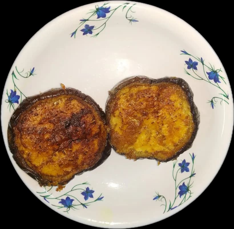 Two rounds of begun bhaja on a flowered plate
