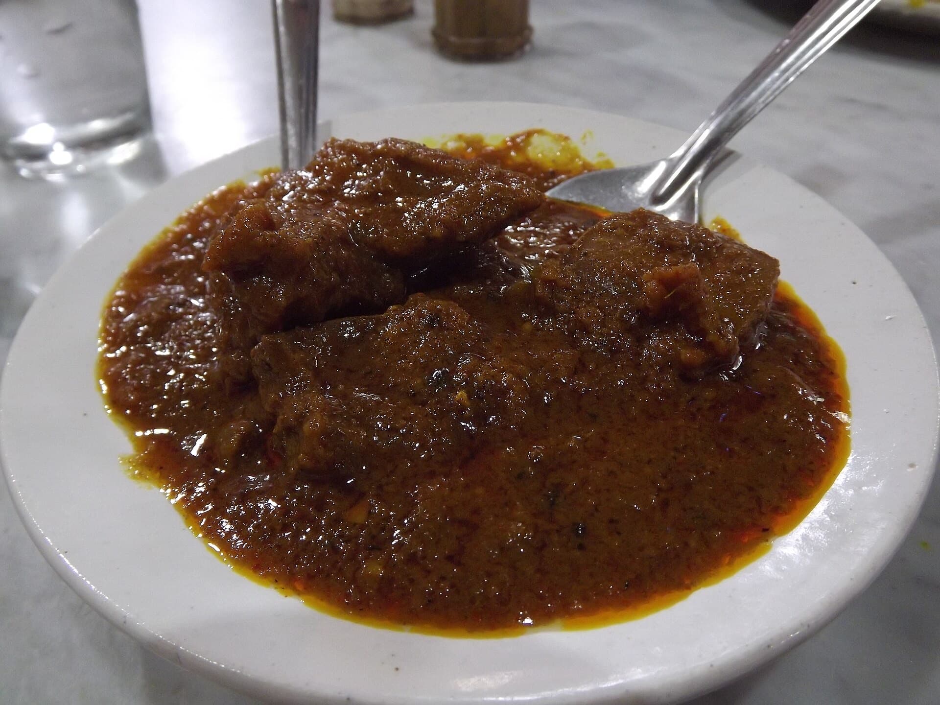 Kosha mangsho, glossy and nearly black, on a white plate