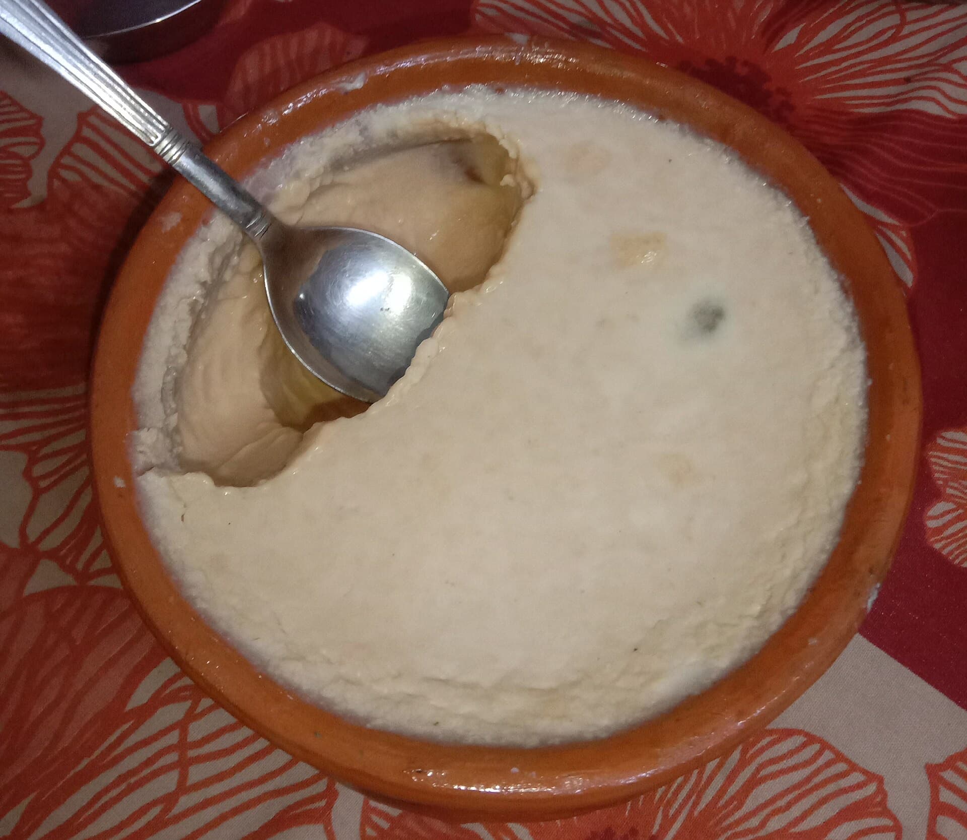 Mishti doi in a clay bowl, with a spoonful already taken