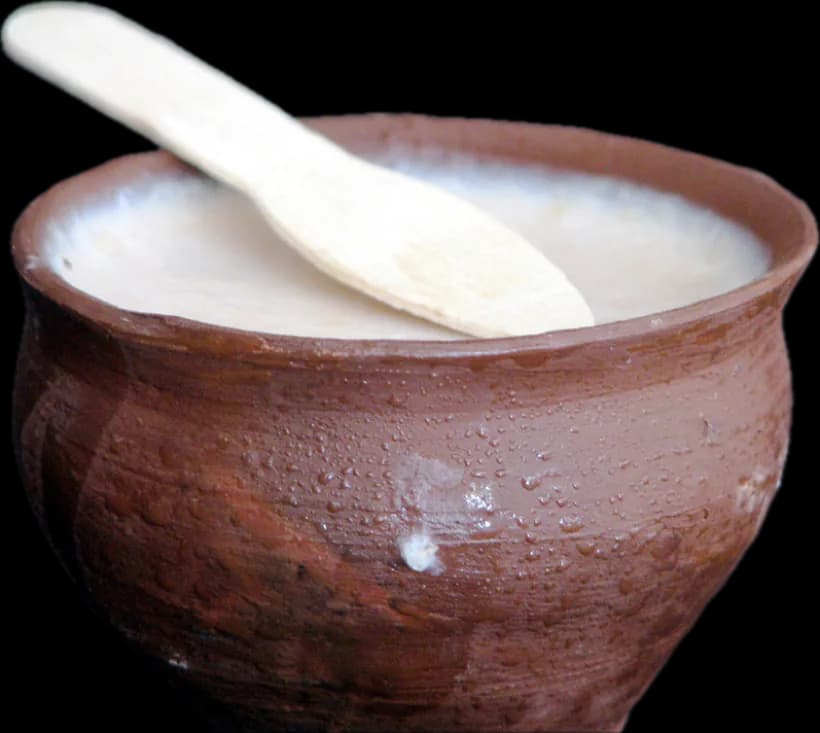 Mishti doi in a clay pot with a wooden spoon