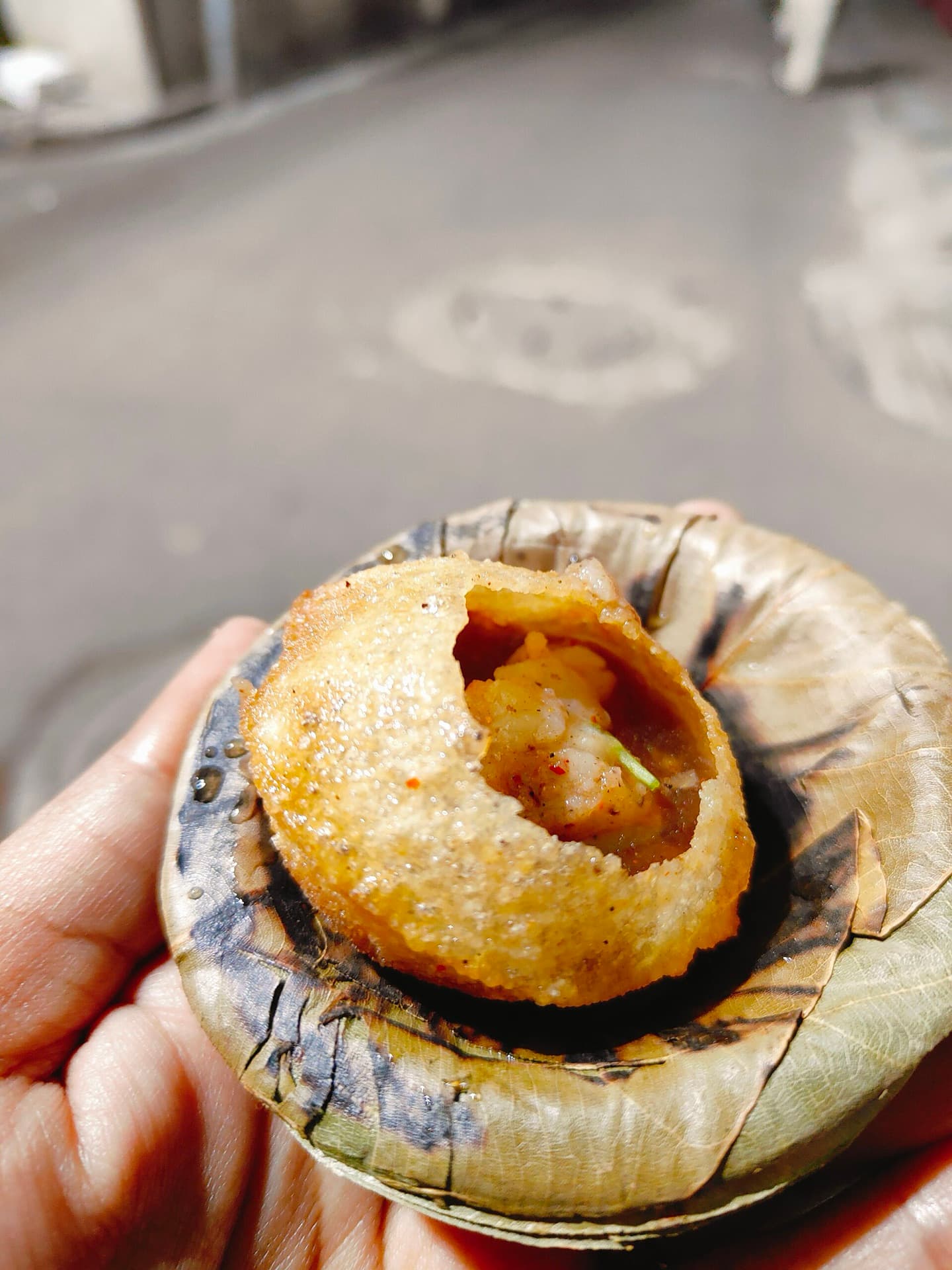 A phuchka held over a sal-leaf bowl