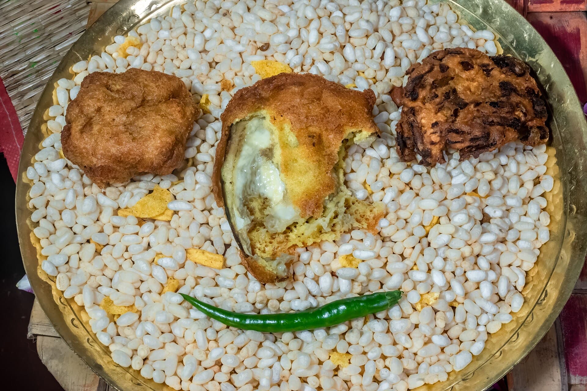 Telebhaja on a heap of muri, with a green chilli